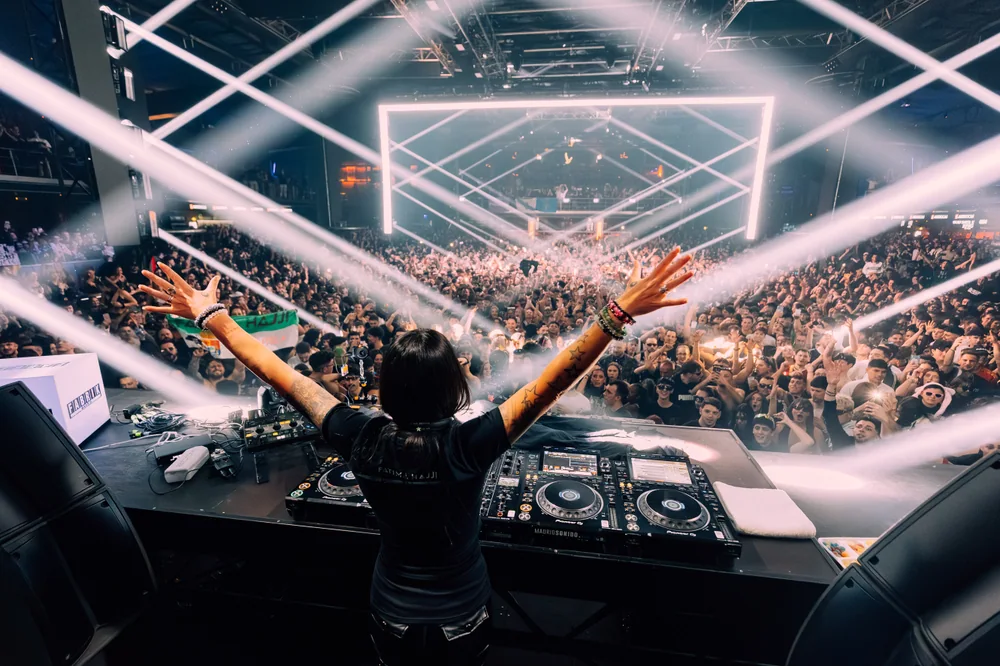 Fatima with her arms open towards the crowd, beneath crossing beams of white light