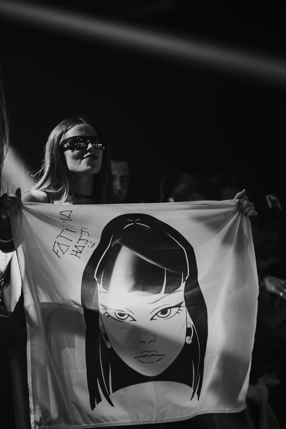 Black and white photograph of Fatima holding a flag with Hajjita’s face